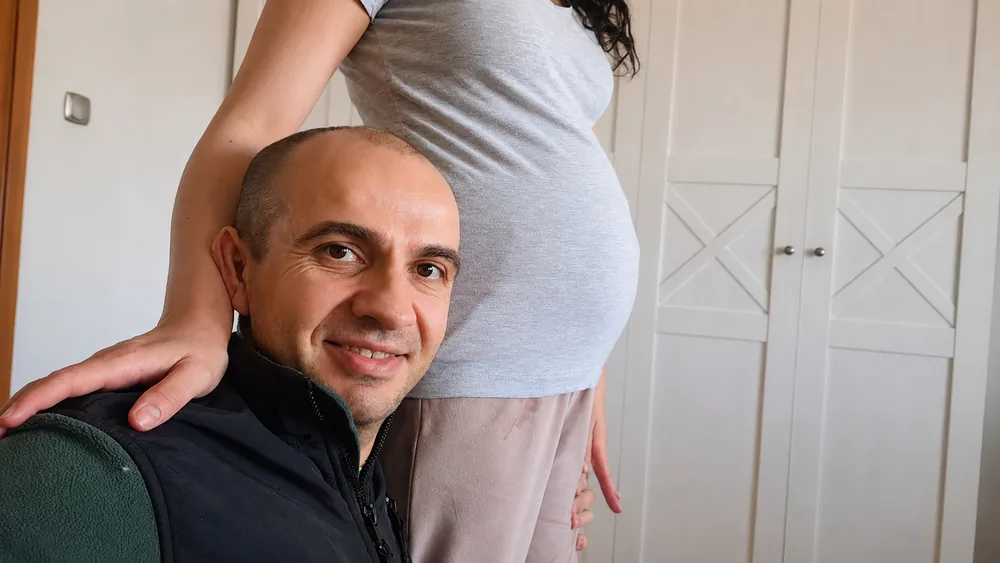 Michał przytula rosnący brzuch Anny w ciąży — twórca PoródNaMiarę.pl w domowym zaciszu przed narodzinami córki